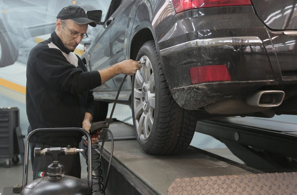 Ask Cars ChatGPT Plugin | Serious car mechanic pumping up car wheel in modern service garage